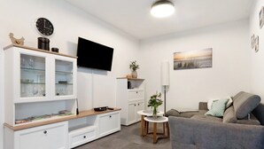 Ein modernes Wohnzimmer mit Flachbildfernseher, einer Couch, einem Couchtisch und einer Vitrine.