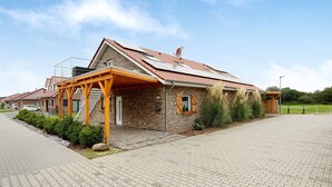 Ein modernes Haus mit Ziegelaußenwand, einem Ziegeldach und einer überdachten Veranda.
