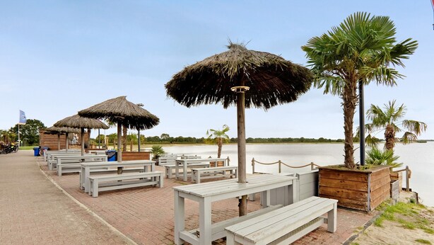 A beachside area with thatched umbrellas, wooden benches, and a view of the water. - Holiday Home "Speicherhäuschen Maike" with Private Garden & Wi-Fi (Geeste)
