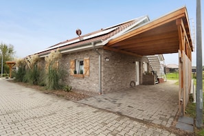 Une maison en briques avec un porche en bois, une petite fenêtre et un chemin en briques.