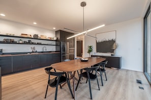 Una cocina moderna con una mesa de comedor de madera y sillas negras, un horno empotrado y un ventanal grande.