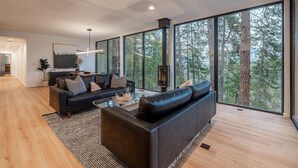 A modern living room with a large window, a fireplace, and a sofa.