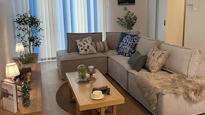 A living room with a sofa, a coffee table, and a striped armchair.