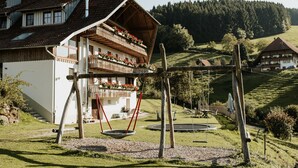 Een klassiek chalet met een houten balkon, een schommel en een tuin.