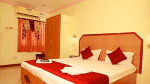Habitación de hotel con una cama grande, cabecera de madera y colcha roja y blanca.