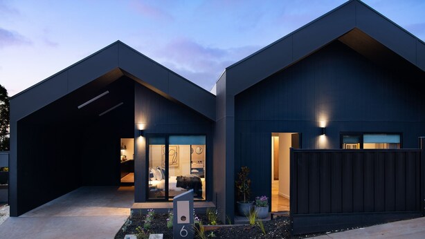 A modern two-story house with a dark exterior, large windows, and a well-lit interior. - Maison Noire- stunning Scandinavian design, great location (Daylesford)
