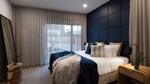 A modern bedroom with a large bed, dark headboard, and a view of the outdoors through sheer curtains. - Maison Noire- stunning Scandinavian design, great location (Daylesford)