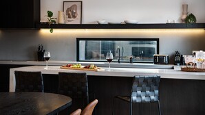 A modern kitchen with a large island, bar stools, a wine glass, and a coffee machine. - Maison Noire- stunning Scandinavian design, great location (Daylesford)