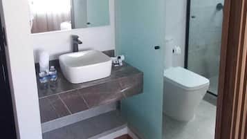 Un baño moderno con un espejo grande, un lavamanos blanco y un box de ducha.