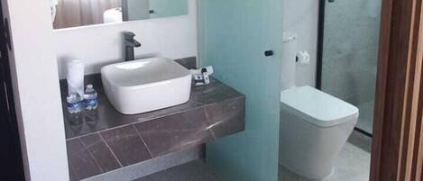 A modern bathroom with a large mirror, a white sink, and a shower enclosure.