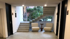 Un pasillo moderno con una escalera que lleva a un balcón, dos sofás y una mesita.