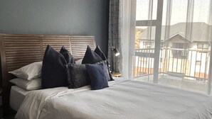 Ein Schlafzimmer mit einem großen Bett, einem Holz-Kopfteil und Blick durch ein Fenster.