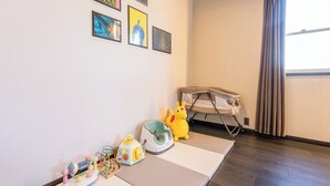 A room with a play area, a window with curtains, and artwork on the wall.