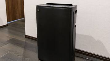 A black refrigerator in a hallway with a wooden floor and white walls.