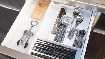 A drawer containing a set of silverware, including a fork, knife, spoon, and chopsticks.