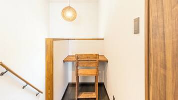 A narrow stairway with a wooden bench at the top, a handrail on the left, and a light fixture above.