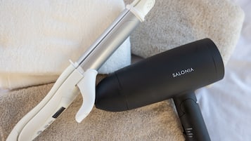 A hair straightener and a black device with the brand name 'SALONIA' on a beige towel.