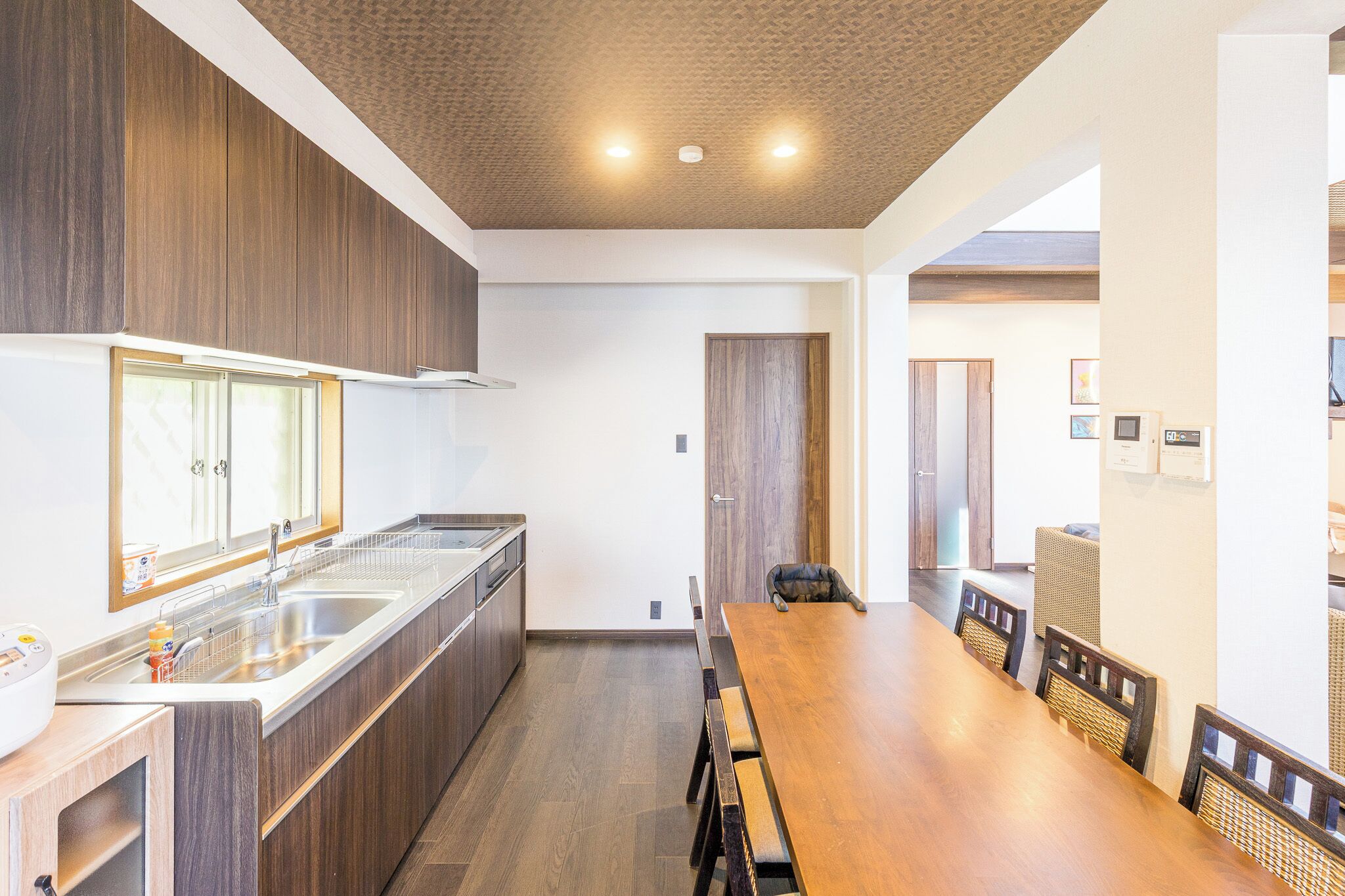 A modern kitchen with wooden cabinets, a stainless steel sink, and a dining area with a wooden table and chairs.