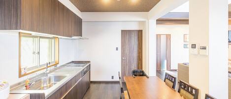 A modern kitchen with wooden cabinets, a stainless steel sink, and a dining area with a wooden table and chairs.