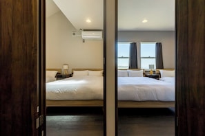 Een hotelkamer met twee bedden, een plafondventilator, een airconditioning en een raam met gordijnen.