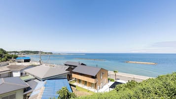 A coastal residential area with houses, a clear sky, and a view of the sea.