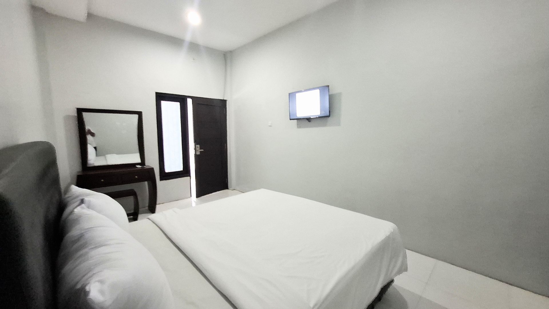 A bedroom with a bed, a dresser, a mirror, and a door.
