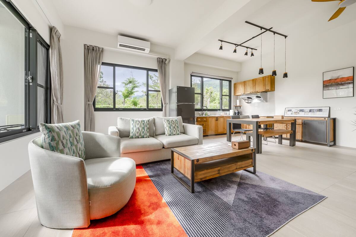 Sala moderna com sofá, mesa de centro e vista para a cozinha.