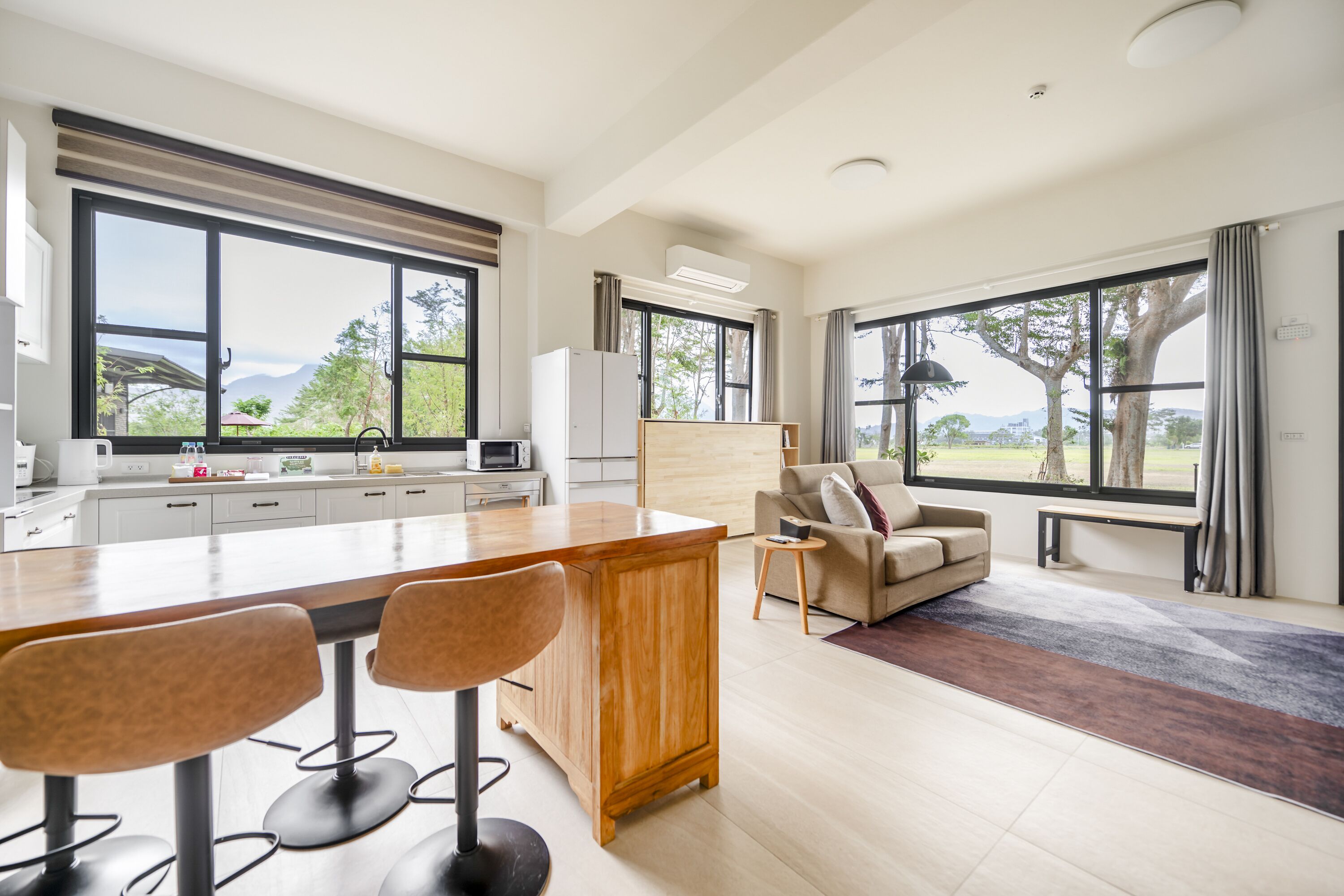 A modern kitchen with a bar area, large windows, and a view of the outdoors.