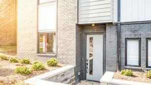 Un bâtiment moderne à deux étages, doté d’une façade en briques, d’une porte grise et de petites fenêtres.