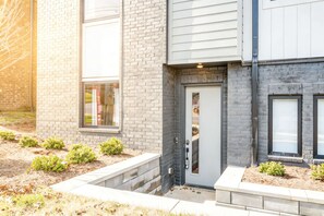 A modern two-story building with a brick facade, a grey door, and small windows.
