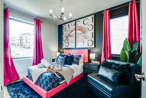 A modern bedroom with a pink bed frame, a large Gucci artwork, and a view of the city.