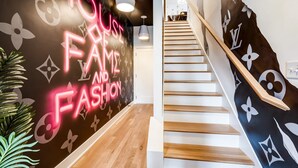 Un escalier avec une rampe en bois et un mur orné d’un motif Louis Vuitton.