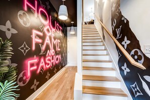 A staircase with a wooden handrail and a wall with a Louis Vuitton pattern.