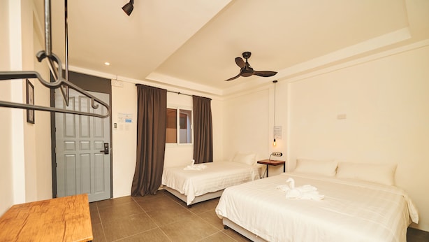 A hotel room with two beds, a wooden table, a ceiling fan, and a door. - Hotel Gray in Boracay (Boracay Island)