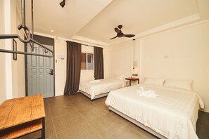 A hotel room with two beds, a wooden table, a ceiling fan, and a door. - Hotel Gray in Boracay (Boracay Island)