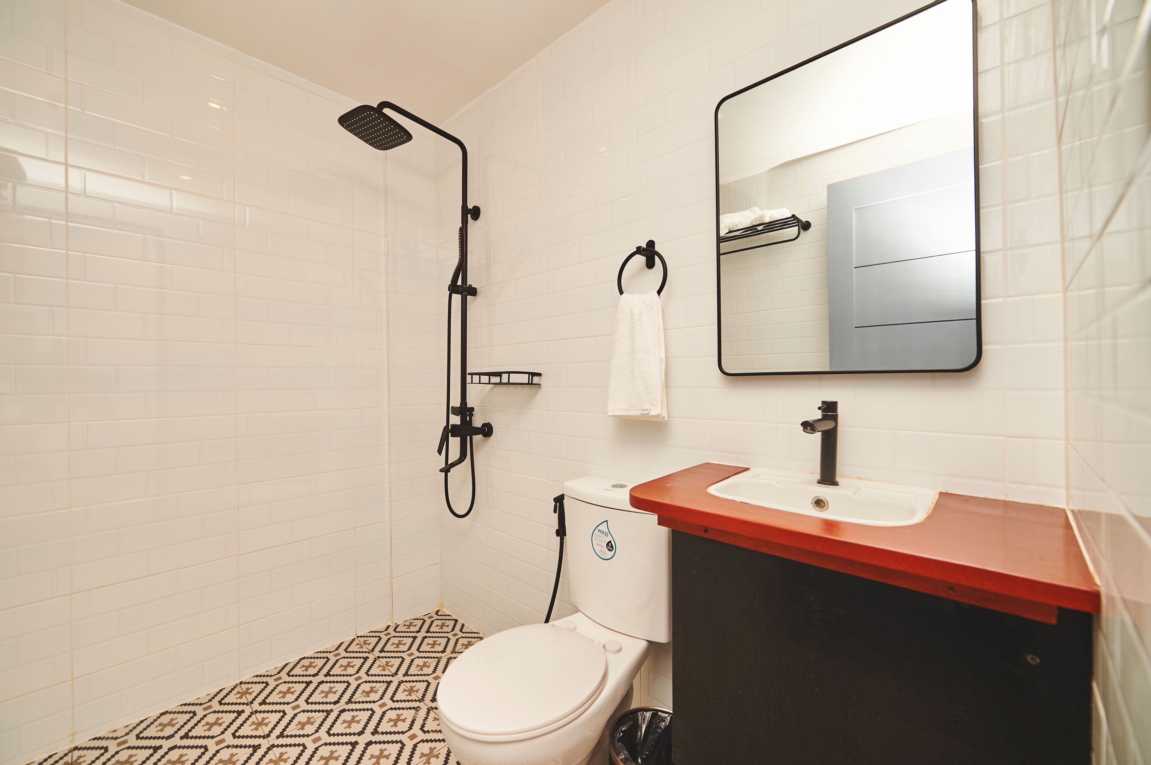 A bathroom with a toilet, sink, mirror, and shower.