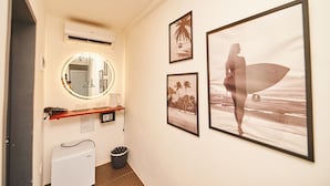 A hallway with a mirror, framed pictures, a small refrigerator, and a trash bin. - Hotel Gray in Boracay (Boracay Island)