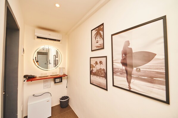 A hallway with a mirror, framed pictures, a small refrigerator, and a trash bin. - Hotel Gray in Boracay (Boracay Island)