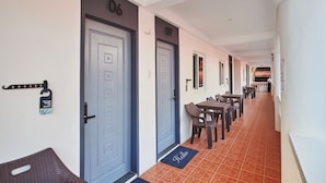 A hotel corridor with numbered doors, a seating area with tables and chairs, and a 'Hello' mat at the entrance. - Hotel Gray in Boracay (Boracay Island)