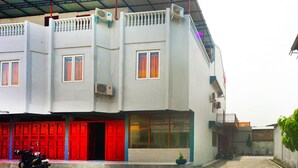 A two-story building with a red door, a balcony, and a motorcycle parked in front. - OYO 93066 D'niel Homestay Syariah (Medan)
