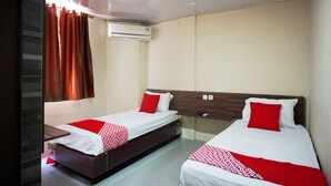 A hotel room with two single beds, each with a red and white bedspread, a wooden headboard, and a window with brown curtains. - OYO 93066 D'niel Homestay Syariah (Medan)