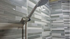 A shower with a handheld showerhead in a tiled bathroom. - OYO 93066 D'niel Homestay Syariah (Medan)