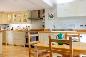 Una cocina con armarios de madera, una estufa y una mesa de comedor con sillas.