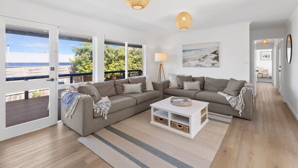 Ein modernes Wohnzimmer mit einem Ecksofa, einem Couchtisch und Blick ins Freie.