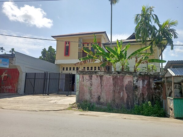 Um edifício de dois andares com fachada amarela e porta vermelha.