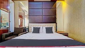Ein großes Bett mit weißer und roter Bettdecke, zwei Kissen und einem Holzkopfteil.