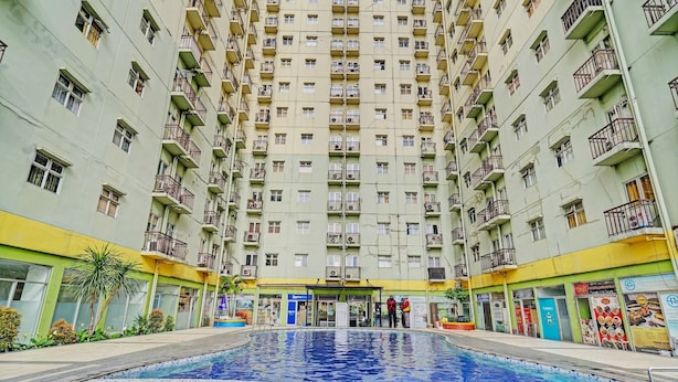 Ein Hochhaus mit Wohneinheiten, einem zentralen Innenhof, der einen Swimmingpool, Balkone und verschiedene Geschäfte bietet.