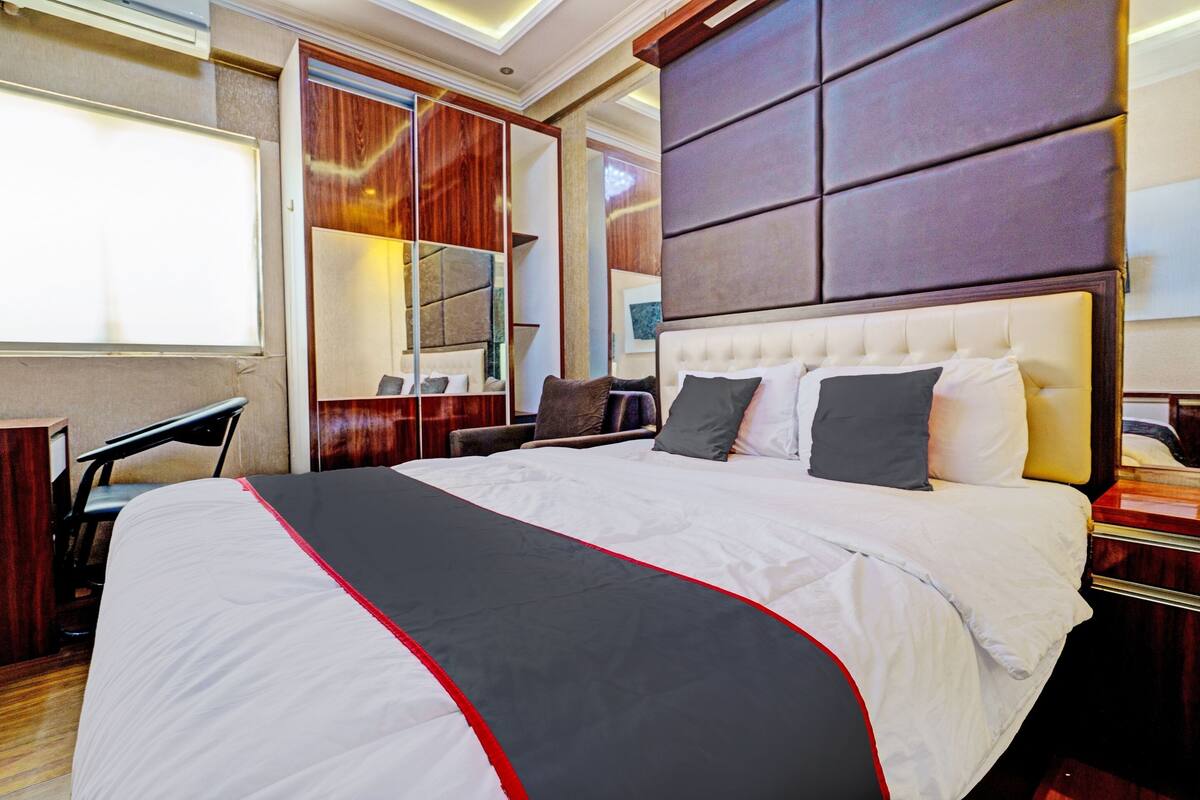 A large bed with a white and red bedspread, a wooden headboard, and a mirror above it.