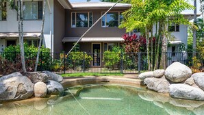 A modern two-story house with a swimming pool surrounded by rocks and tropical plants. - 5 Reef Terraces Port Douglas (Port Douglas)