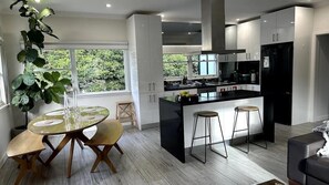 Een moderne keuken met witte kasten, een zwart aanrecht en een centraal kookeiland met barkrukken.